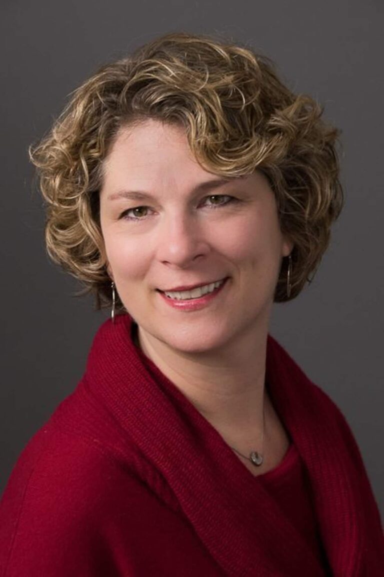 Headshot portrait of a woman wearing a red sweater.