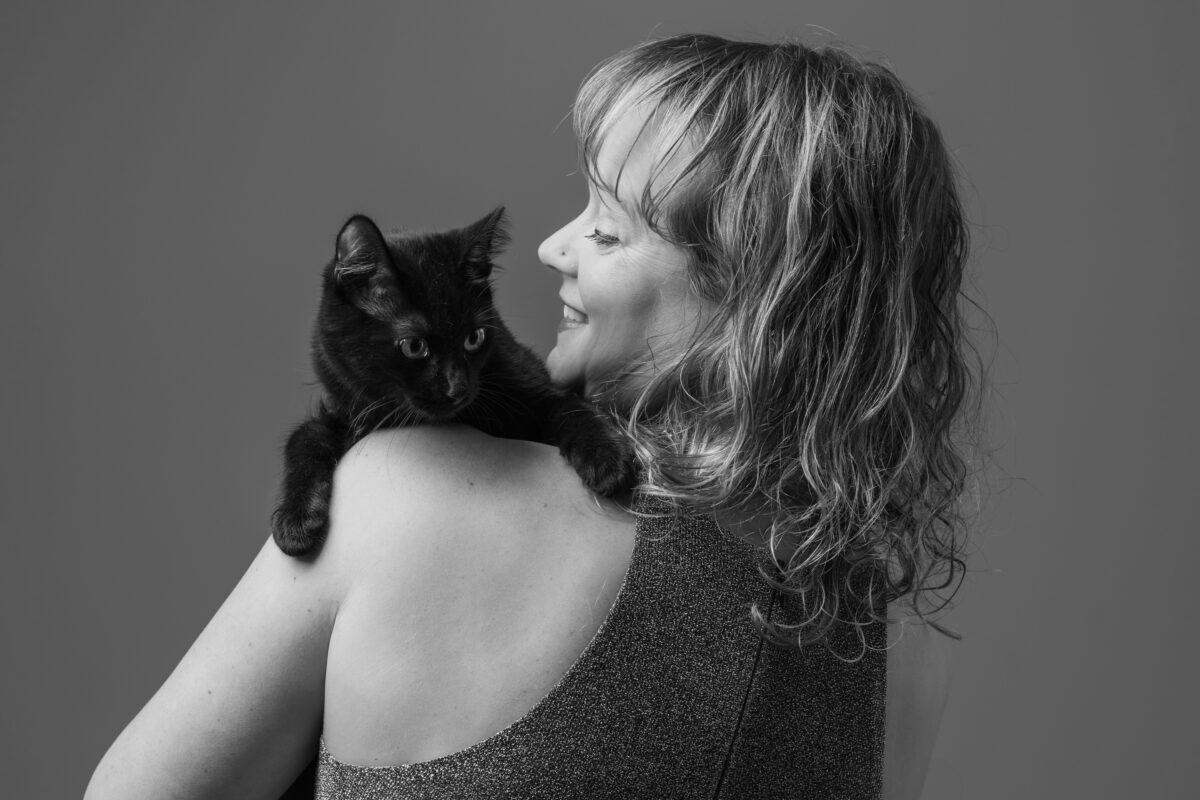 Black and white pet portrait of a woman with a black kitten